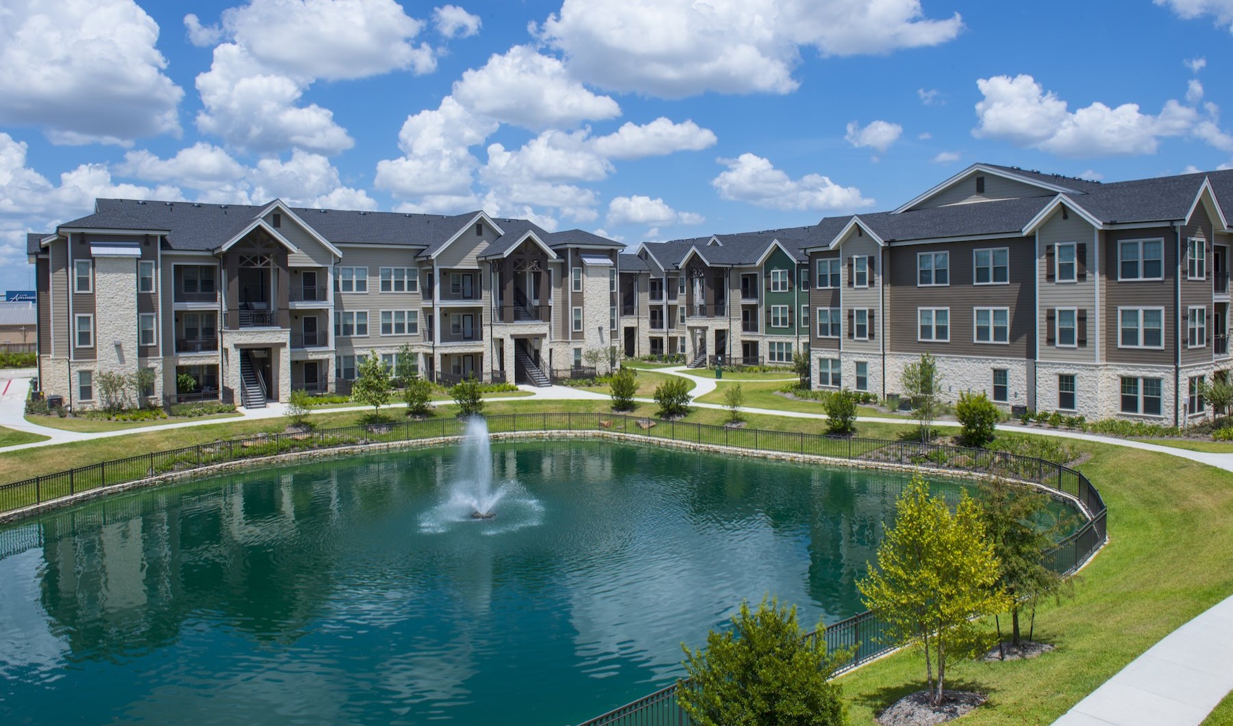 a large apartment complex next to a body of water with a fountain