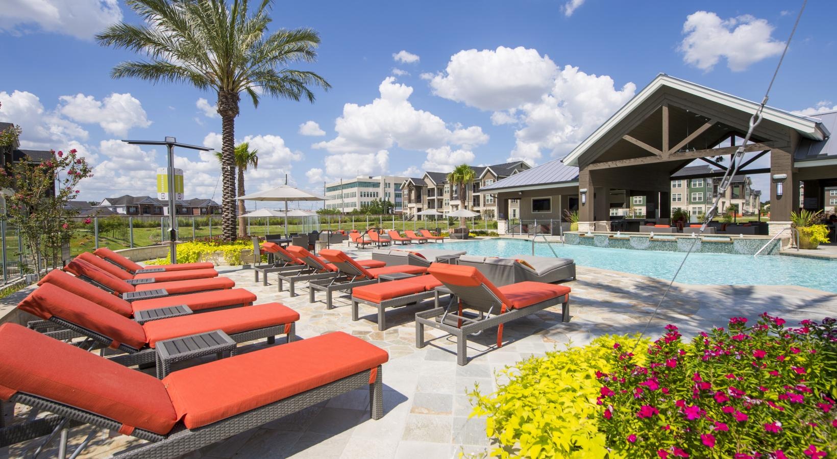 a pool with lounge chairs and tables by it